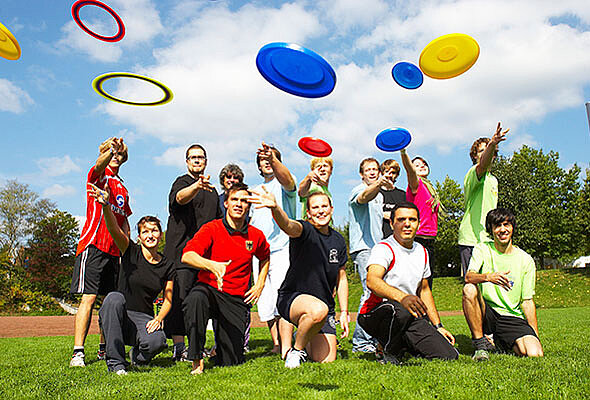 Sporthelferinnen und Sporthelfer werfen mit Frisbee